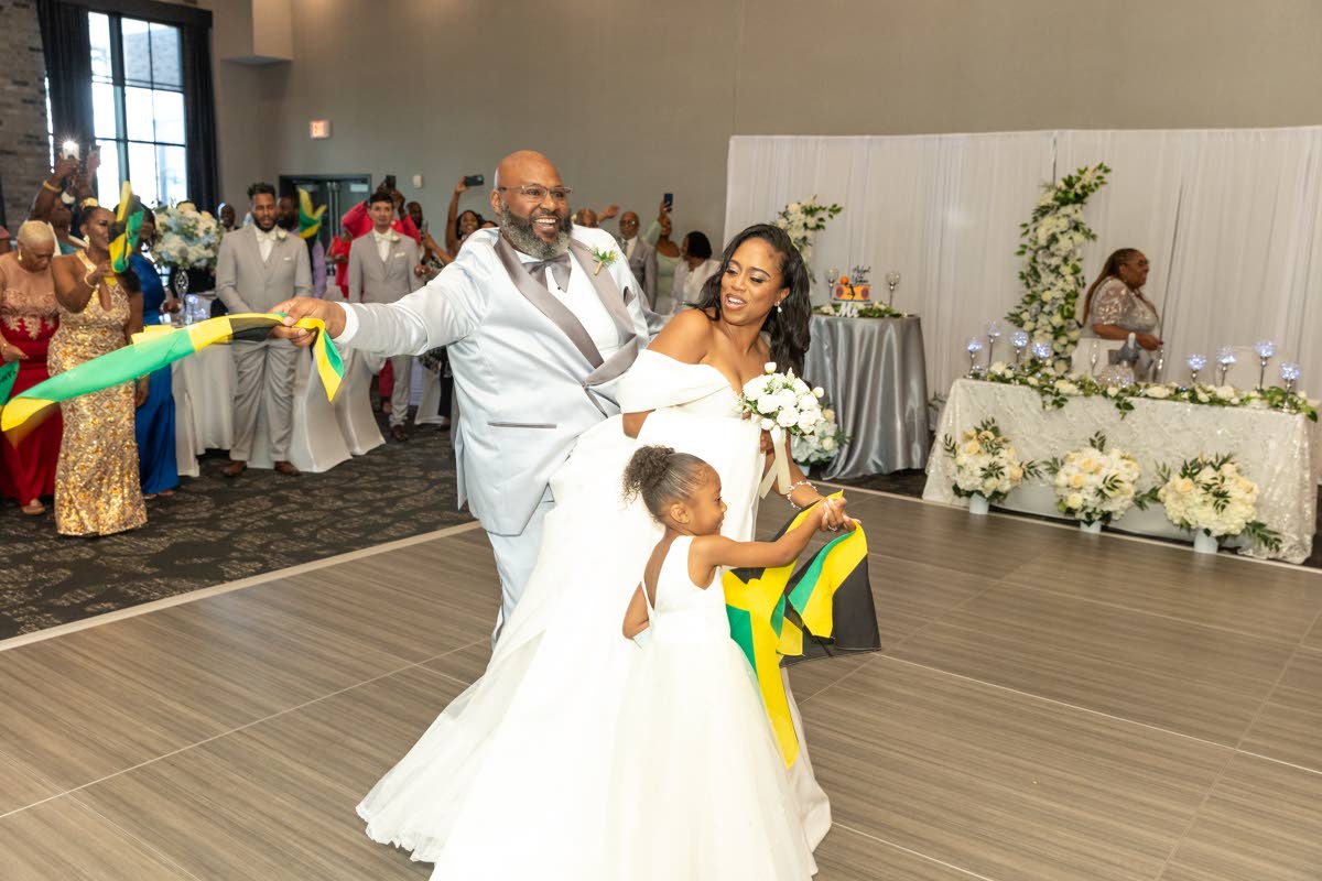 Michael and Yvonne make their entrance to the wedding reception, waving the Jamaican flag with daughter, Nuri Rawles, in the midst of it all.
