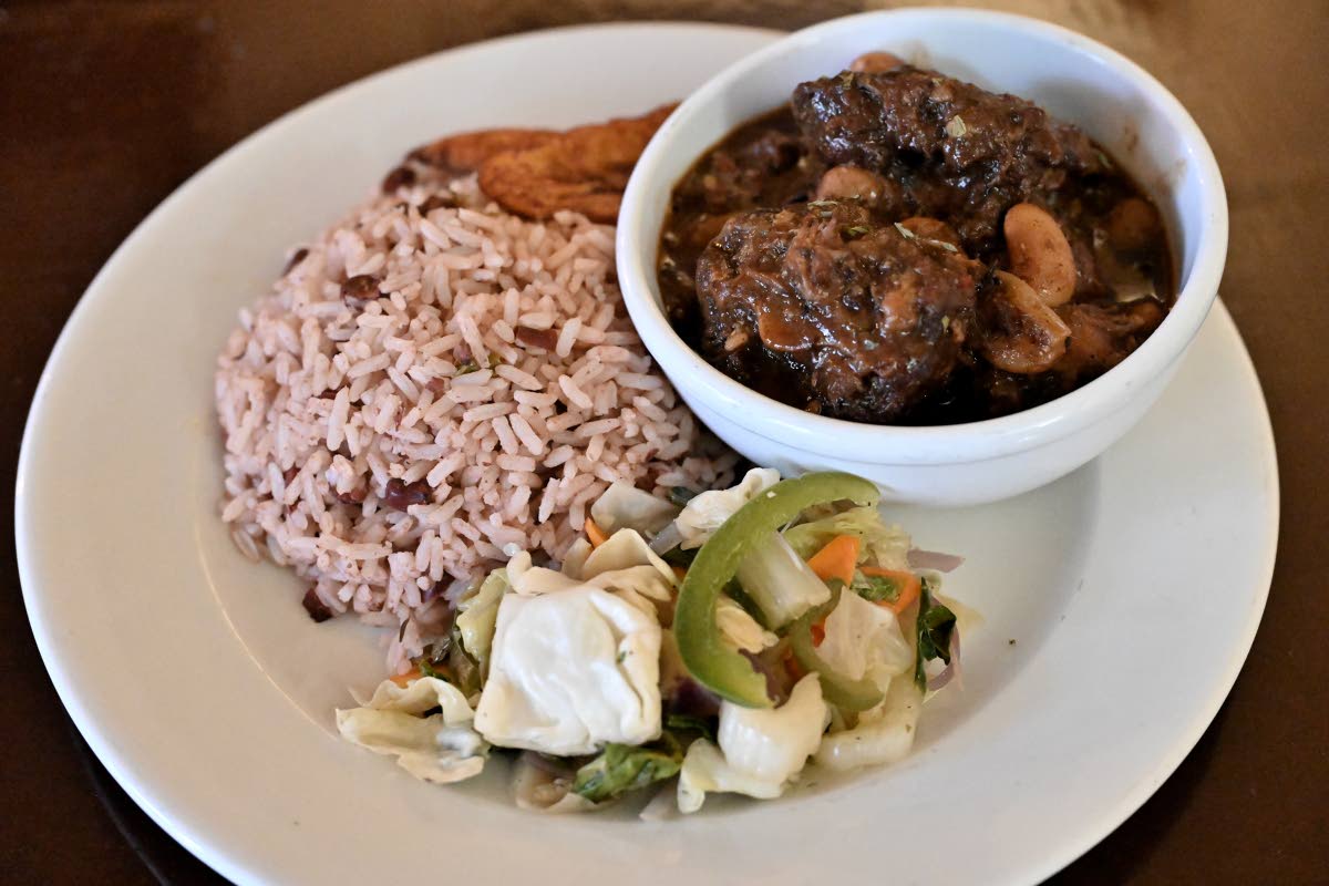 Oxtail is paired with rice and peas, steamed vegetables and fried plantains.