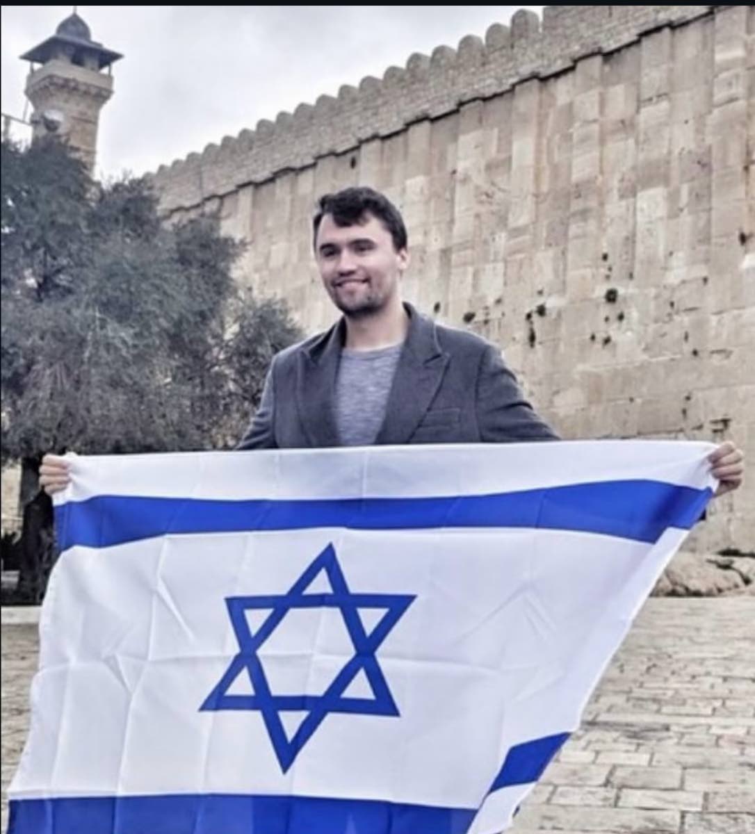 Iconic photo of Charlie Kirk standing in front of the ‘Tomb of Our Patriarchs’ in the holy city of Hebron in Israel, holding an Israeli flag.