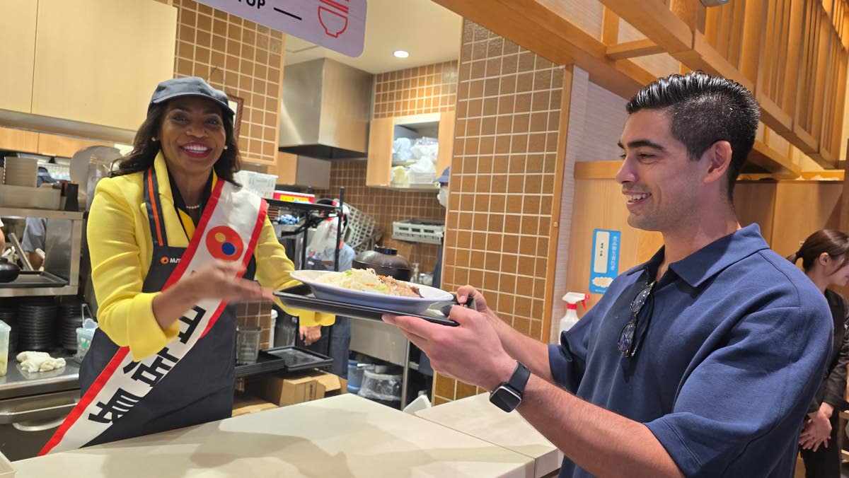 Jamaican Ambassador to Japan, Shorna-Kay Richards (left), serves a jerk chicken meal to Tatsuya Lacey on Tuesday at the Japanese restaurant Matsuya, which now carries the Jamaican dish in their more than 1100 restaurants across Japan. 
