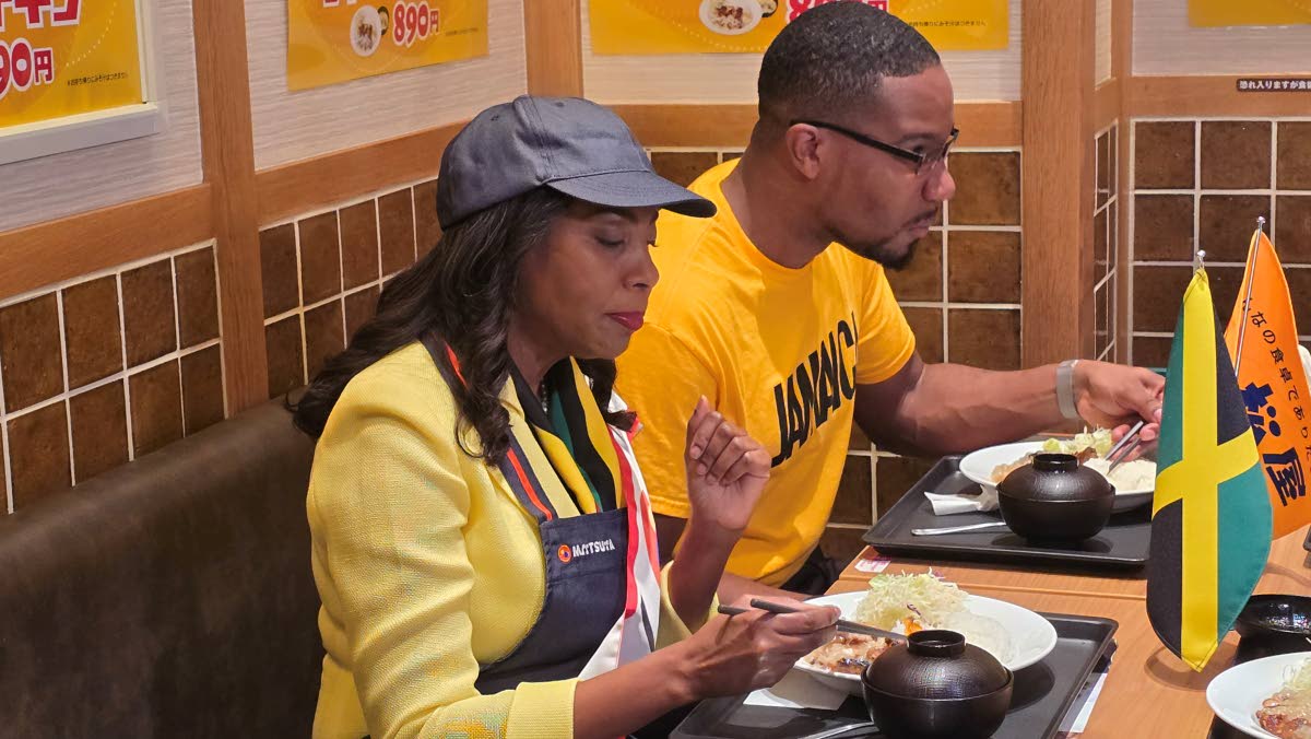 Jamaican Ambassador to Japan, Shorna-Kay Richards (left), and First Secretary Alexander Dixon enjoy a meal of jerk chicken at the Matsuya Restaurant in Tokyo on Tuesday. 
