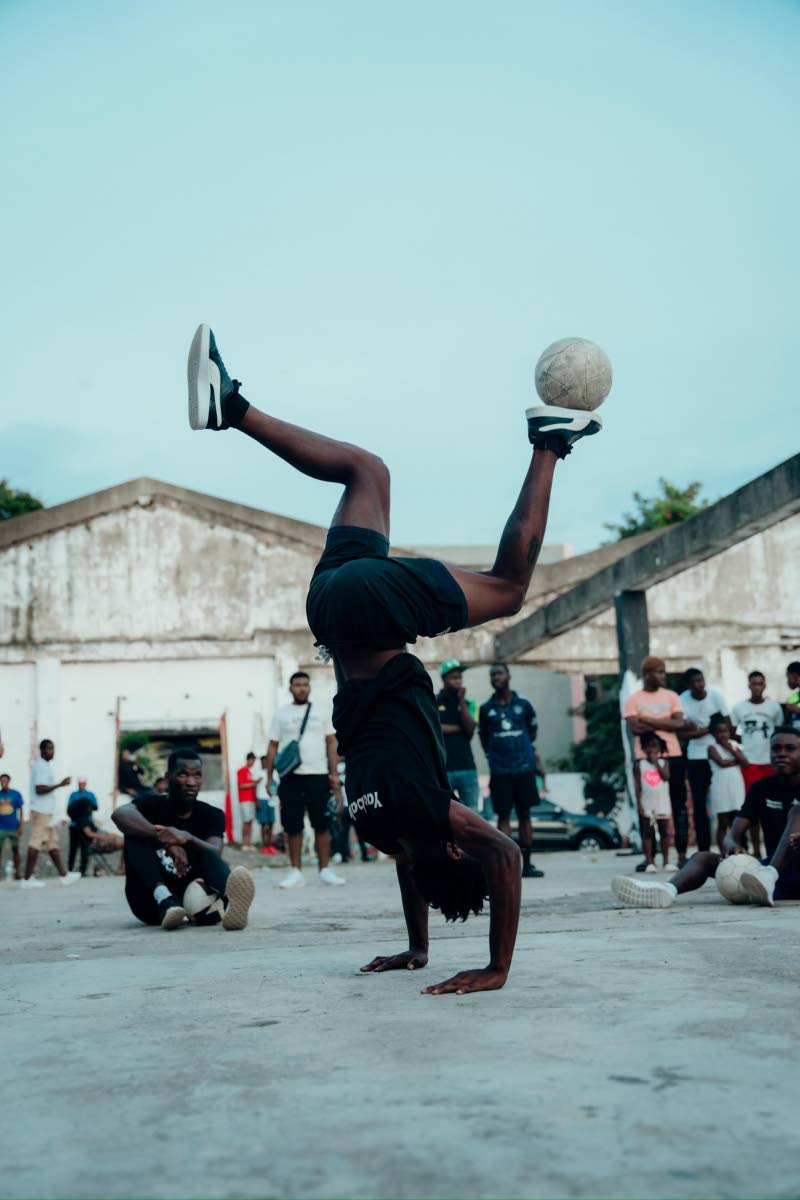 National Football Freestyle Champion John Manradge juggles a ball while performing a handstand.