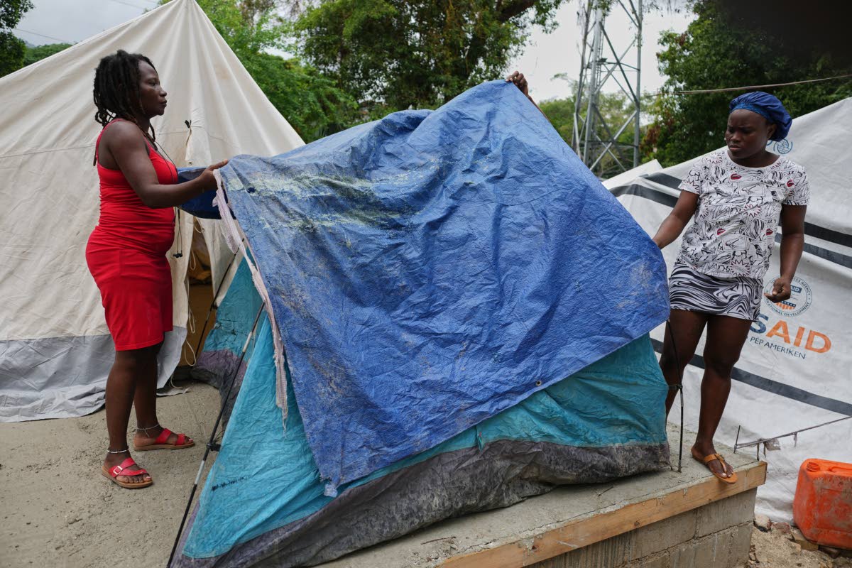 People place plastic tarps over their tents ahead of expected rain at a shelter for families displaced by gang violence in Port-au-Prince, Haiti.