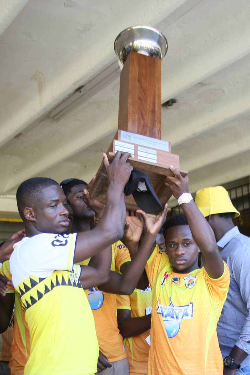 Garvey Maceo High’s head coach Lester Hibbert (left) and team captain Christopher Mundle lift the daCosta Cup during celebrations at the school on Monday, December 9, 2024.
