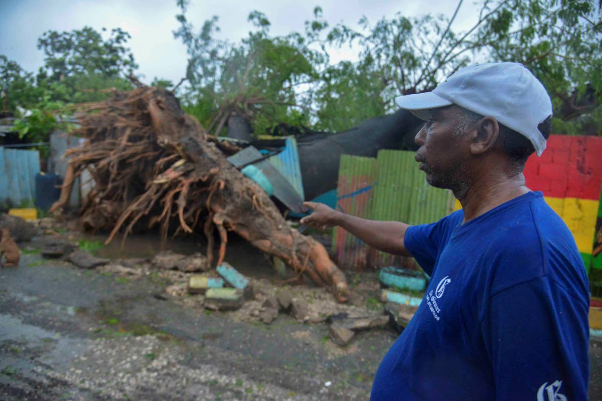 Clive Evans, a resident of Walker’s Avenue in Gregory Park, St Catherine, looks at the damage to his house caused by a fallen tree during Hurricane Melissa on Tuesday.