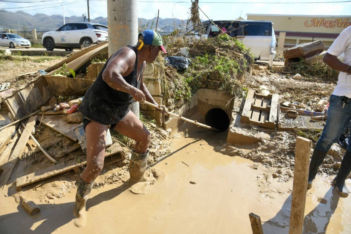 Rose Holness clears mud from her property in Catherine Hall, St James. 
