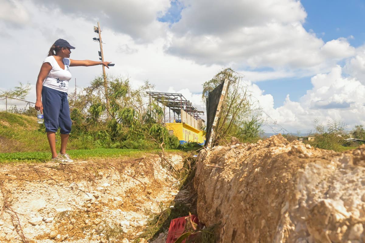 St Elizabeth Technical High School (STETHS) Acting Vice Principal, Patrine Daley-Chambers, points to the section of the perimeter wall that broke away during the passage of Hurricane Melissa.