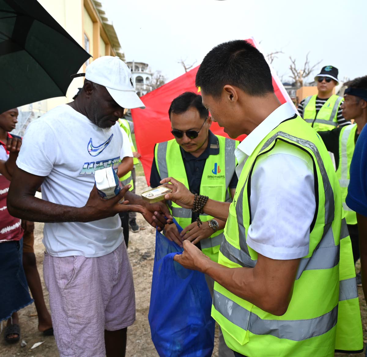 From left: Mark Orville Kerr, a resident of Rowe in Whitehouse, Westmoreland, is shown items from a care package by Shifu Huang, CEO of Caribbean Solar Life, and Yangsen Li, CEO of LCH Developments, on Wednesday. 