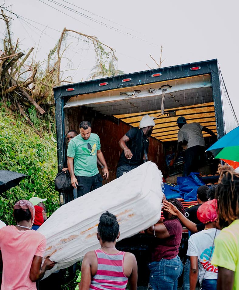Stewart (left, standing in truck) and team distribute supplies to hurricane-impacted persons in Hanover.
