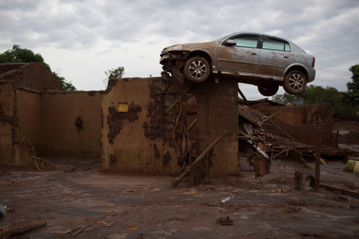 In this November 23, 2015 photo, a car sits on top of a wall of a home, destroyed when a dam burst in Bento Rodrigues, Brazil.