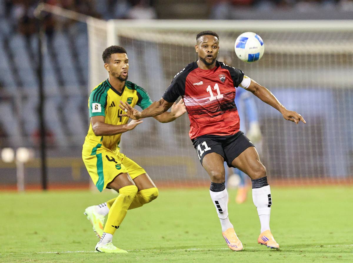 Mason Holgate (left) tussles for the ball against Trinidad and Tobago skipper Levi García during their Concacaf World Cup Qualifier at the Hasely Crawford Stadium on Thursday.