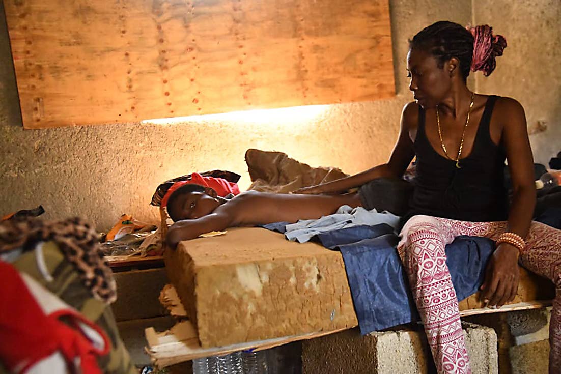 IIn this November 2025 photo, Joel Wynter, who is suffering from sickle-cell disease, is being tended to by his mother under a makeshift shelter after their house was damaged by Hurricane Melissa. 