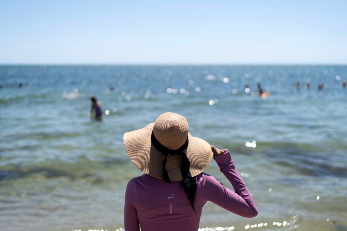Ruth Wilson, who has lupus and is sensitive to the sun, stands at the water’s edge while at the beach with family in August in South Yarmouth, Massachusetts.