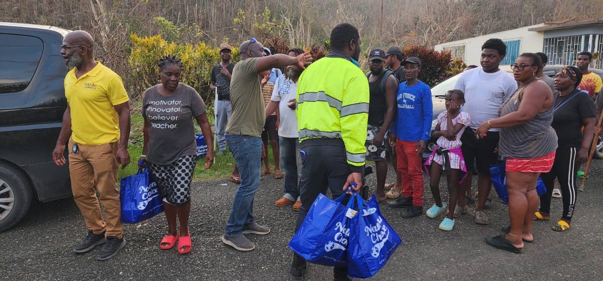 Residents of Carisbrook in St Elizabeth walk away with care packages containing food, water, and hygiene supplies distributed by the RG CARES outreach team, offering essential support following the impact of Hurricane Melissa.