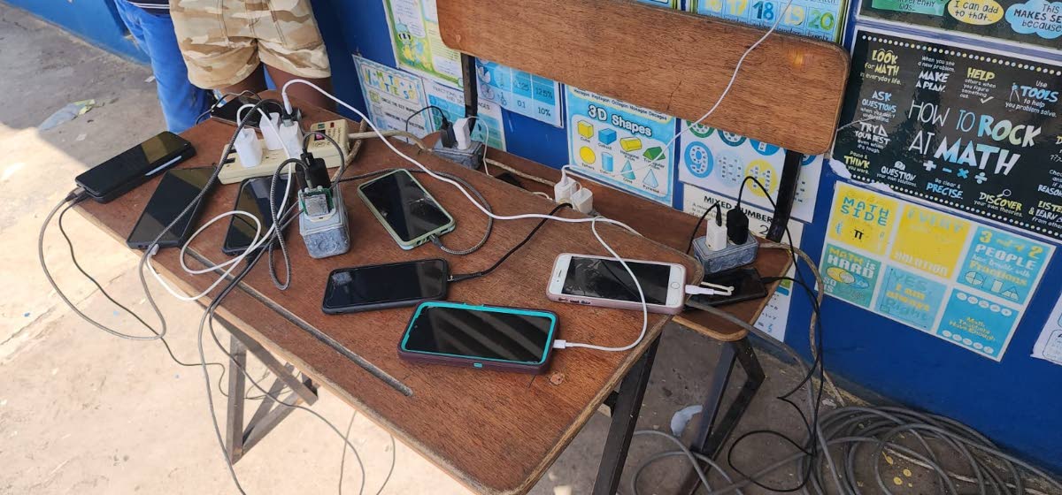 Residents of the Lacovia Primary School shelter in St Elizabeth charge their phones using power supplied by the RG CARES outreach team; providing critical connectivity after the widespread devastation and dislocation caused by Hurricane Melissa.