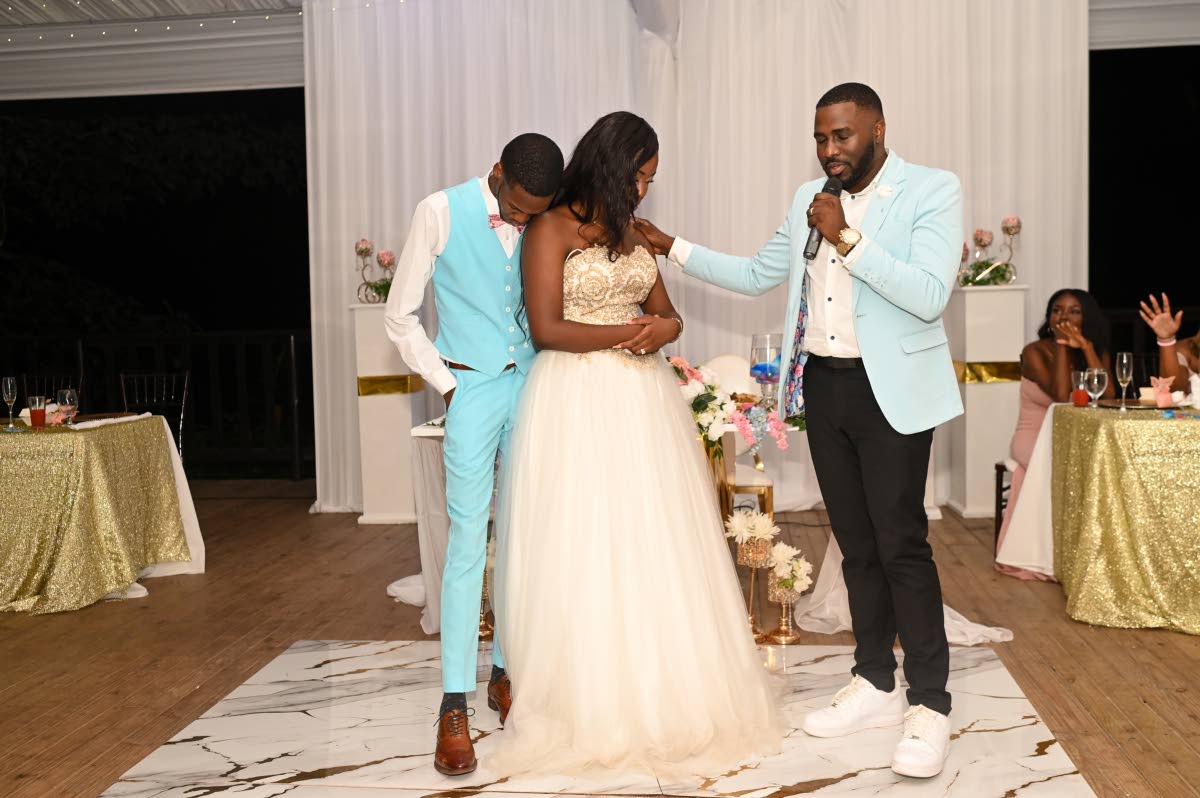 Dane (left) and Abbiegale bow their heads in a moment of gratitude as Pastor Michael Craigg prays over their blessed union.