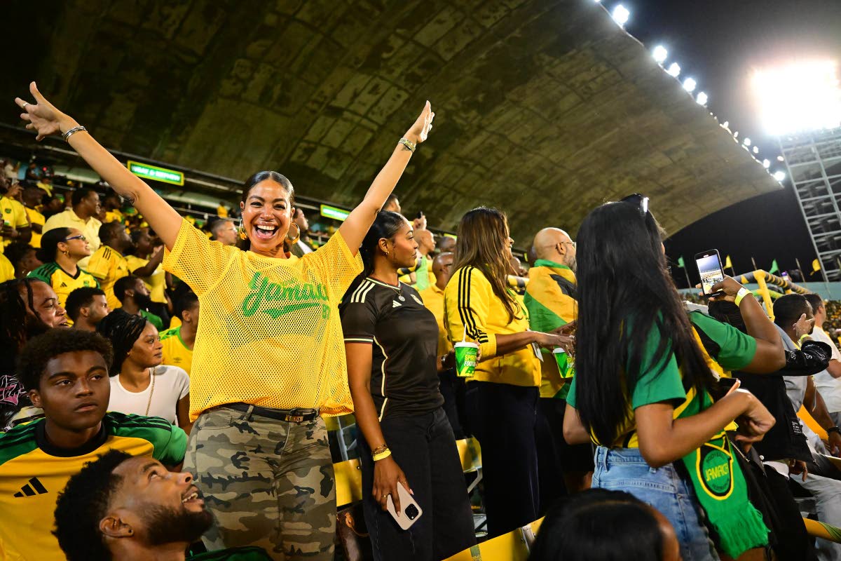 A buoyant Yendi Phillipps reps Jamaica in a yellow Represent Jamaica mesh jersey, paired with camo cargo pants.