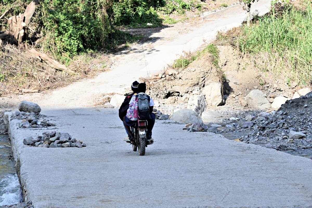 A schoolgirl rides pillion on her way home from school last week.