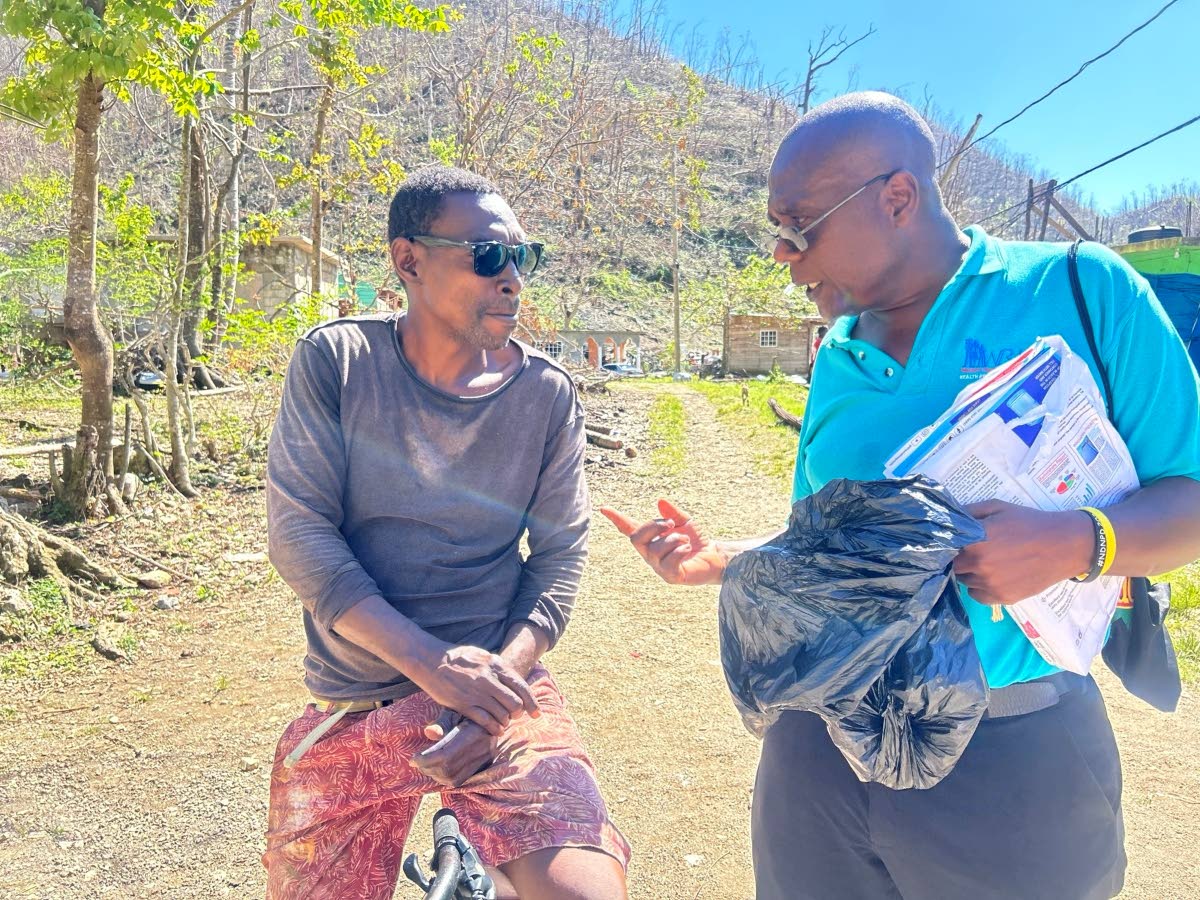 Health Promotion and Education Officer for Westmoreland, Gerald Miller (right), educates a resident on the dangers of contracting leptospirosis and other diseases from the nearby Ancho River.