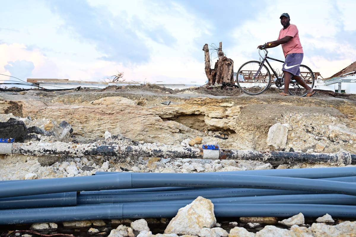 
A pedal cyclist in St Elizabeth walks with his bicycle around an area of roadway which once covered pipes and cables in the aftermath of Hurricane Melissa.  