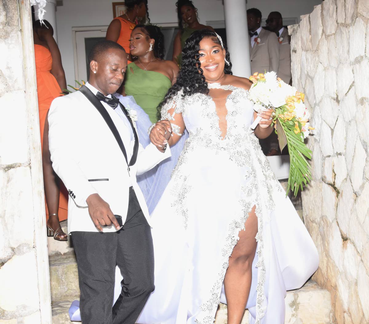 Jevaughn leads his wife, Jordine, down the stairs of their wedding venue.