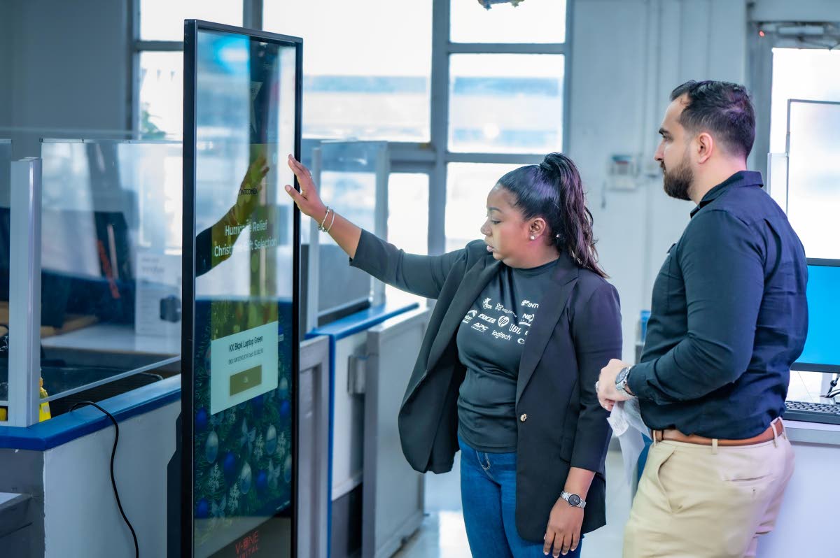 Chrysta-Jaye Walker (left), category manager, printing, consumables and HP systems at Intcomex Jamaica, leads a demonstration of available gift items for Amit Mahbubani, General Manager of ROK Hotel Kingston at Intcomex Jamaica Hurricane Melissa Relief Lau