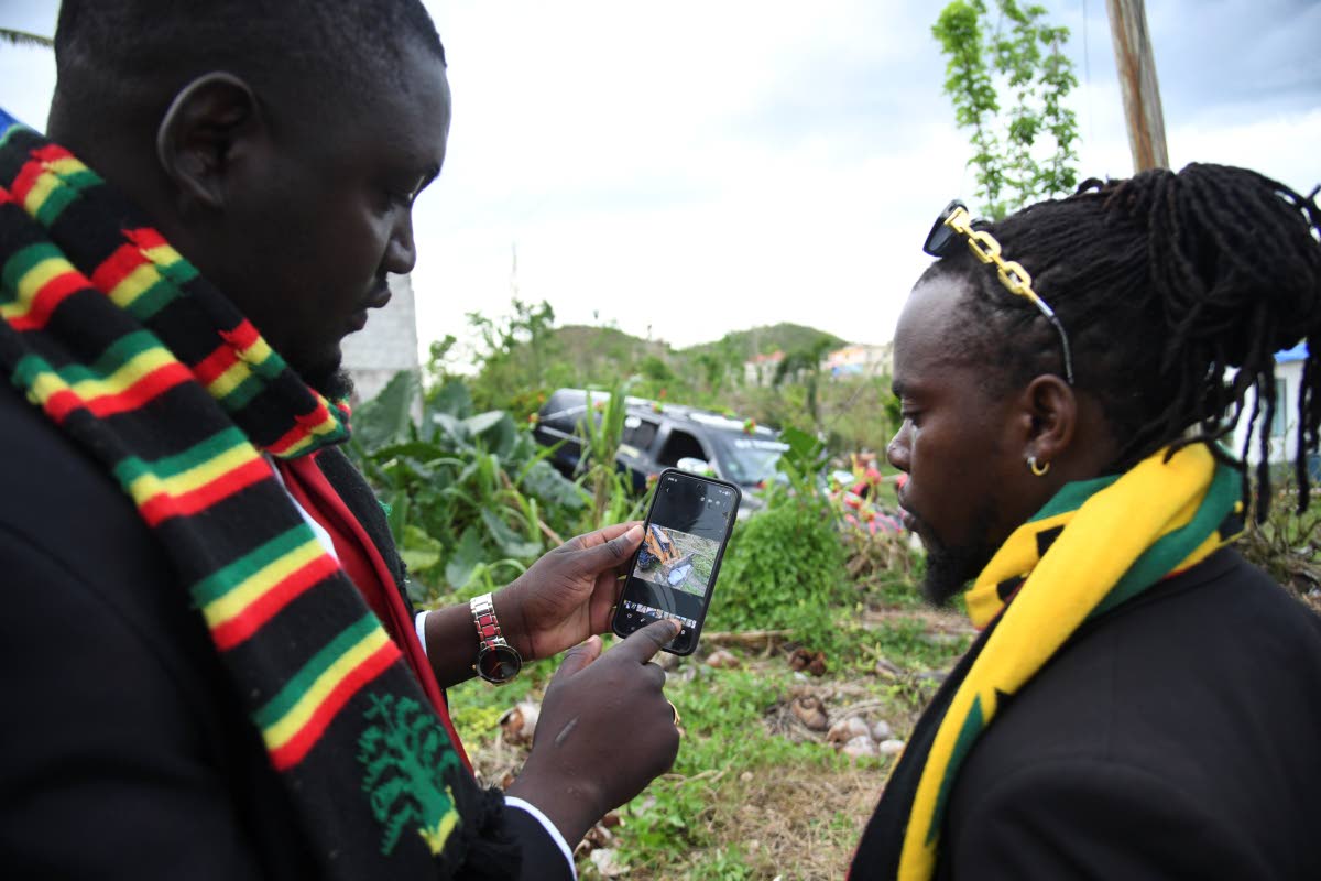 Brandon Thomas (left), CEO of BT Thomas Funeral Home in St Elizabeth, and mortician Okello Piper show a photo of a tractor carrying the body of one of Hurricane Melissa’s victims.