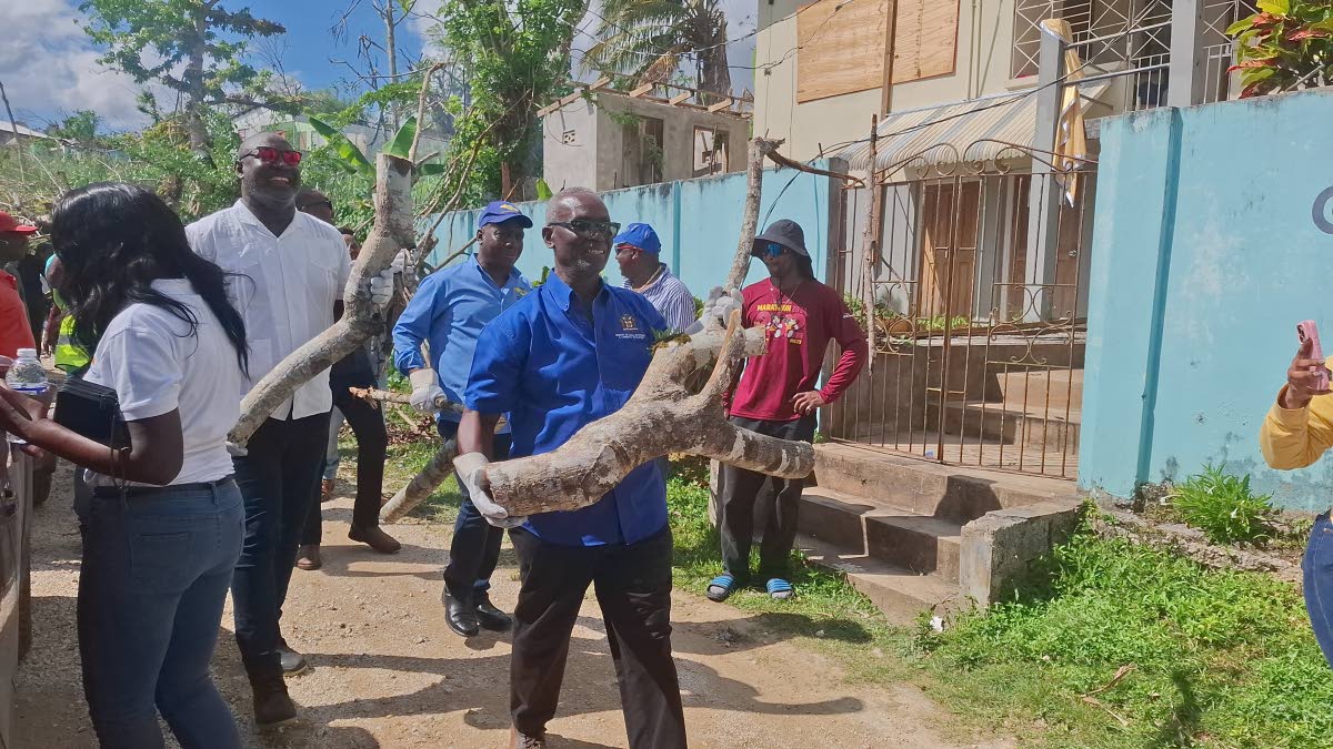 Desmond McKenzie (right), minister of local government and community development, and Dr Dayton Campbell left), member of parliament for Eastern Westmoreland, lead by example yesterday, assisting in removing debris to help restore community spaces in the p