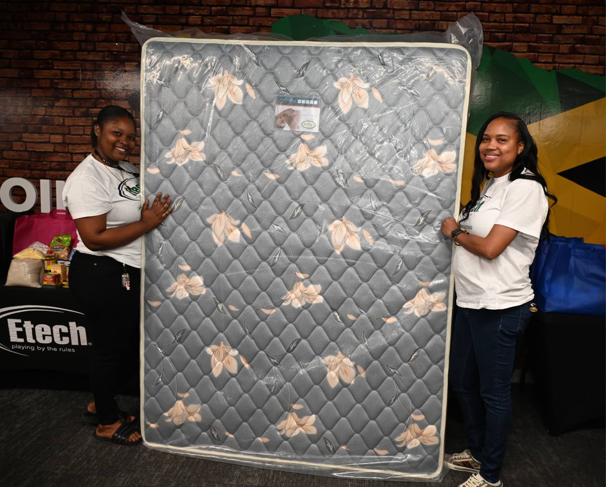 Aleshia Malcolm, an employee of Strobe Etech Communications, receives a mattress from Yanique Troupe, the company’s country manager.