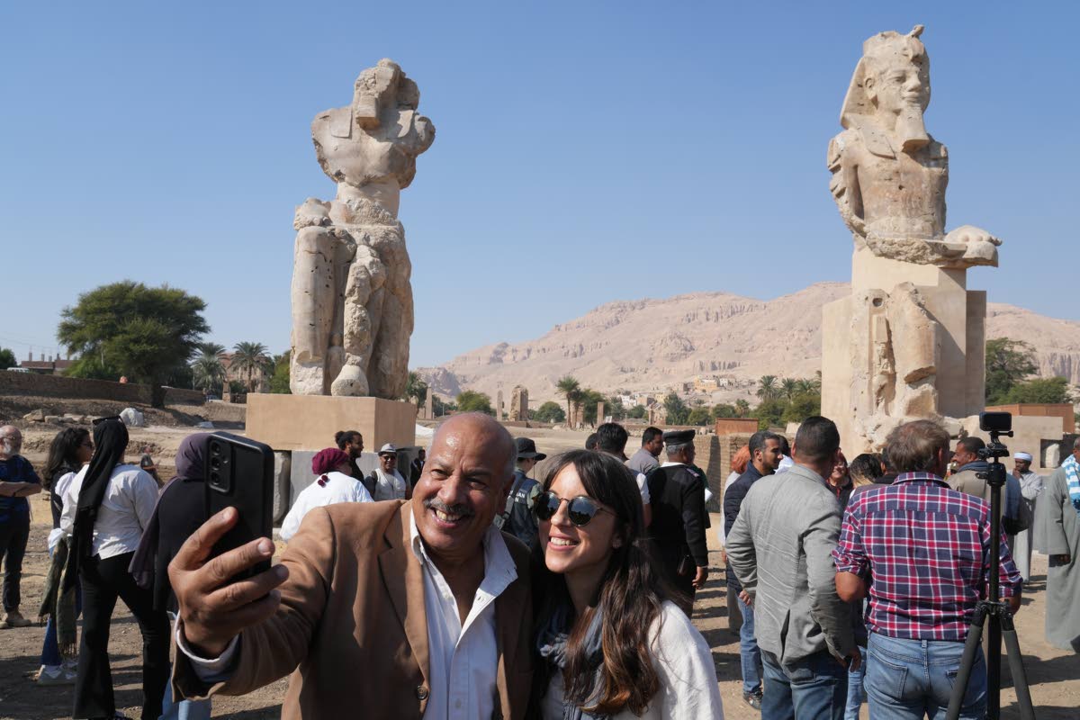 Visitors take photos with the two giant reassembled alabaster statues of Pharaoh Amenhotep III.