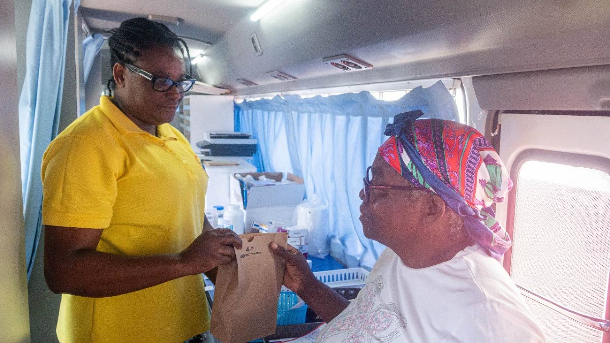 Robertha Carter (left), pharmacy technician, National Health Fund, presents Dorrett Burton with her free prescription drugs after Burton was examined by a doctor at the Hurricane Recovery Health Clinic in Thornton, St Elizabeth.