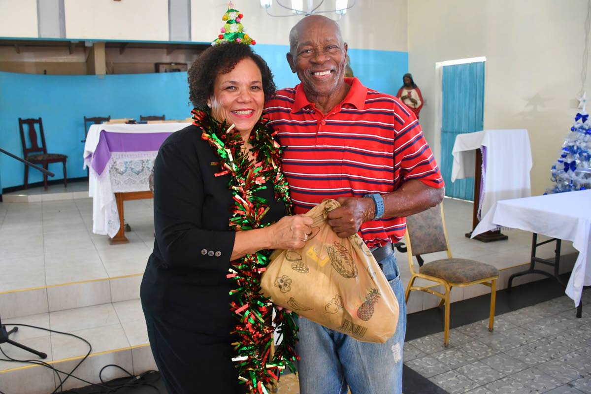President of the Shipping Association of Jamaica, Corah Ann Robertson‑Sylvester, presents a Christmas hamper to Henry Morris, an elderly resident of Greenwich Farm.