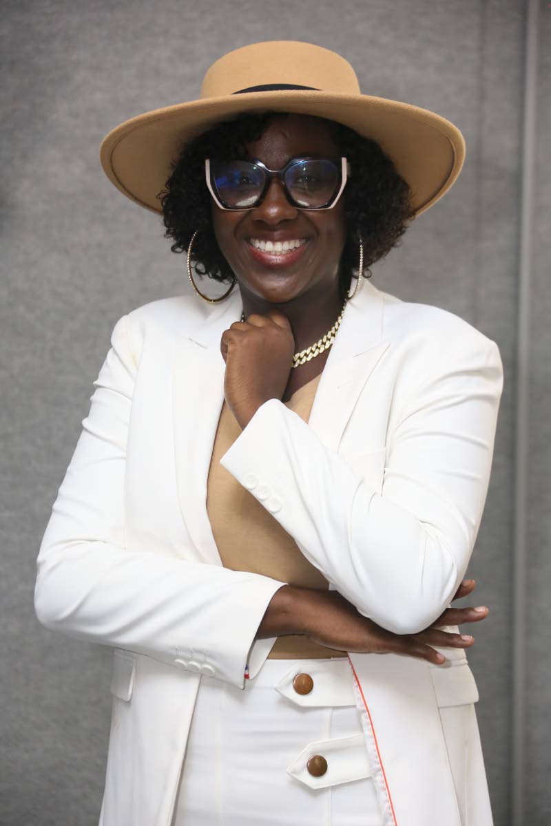 Kathy ‘Tan Deh Deh’ Grant poses for the camera in a white suit, a tan fedora, and a matching camisole and statement specs. 
