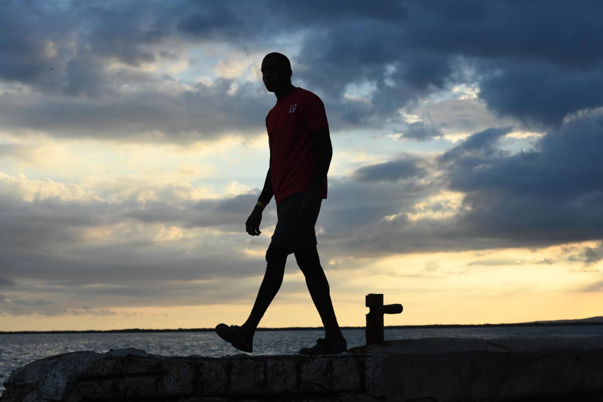 A lifeguard walks along Kingston Harbour as the final sunset of 2025 fades.