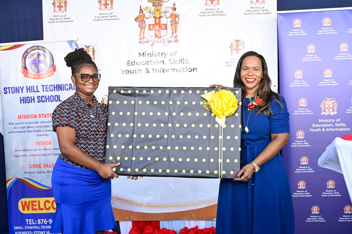 Permanent Secretary in the Ministry of Education, Skills, Youth and Information, Dr Kasan Troupe (right), receives a token from Stony Hill Technical High School teacher Oneisha Lawrence.