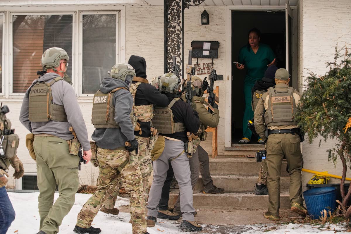 Teyana Gibson Brown, second from right, wife of Garrison Gibson, reacts after a federal immigration officer used a battering ram to break down a door before arresting Garrison Gibson Minneapolis. 