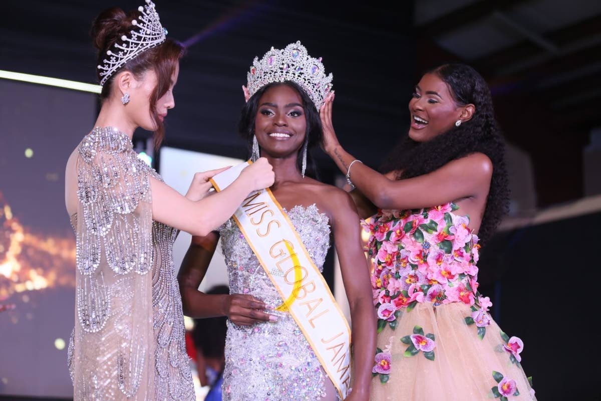 Former Miss Global Jamaica Keri-Ann Greenwood (right) passes the crown to Miss Global Jamaica 2026 Deidrian Downer (centre) at the Douglas Orane Auditorium at the Wolmers Boys’ School on Sunday morning. Fixing her sash is Miss Global 2025 Nhu Van.