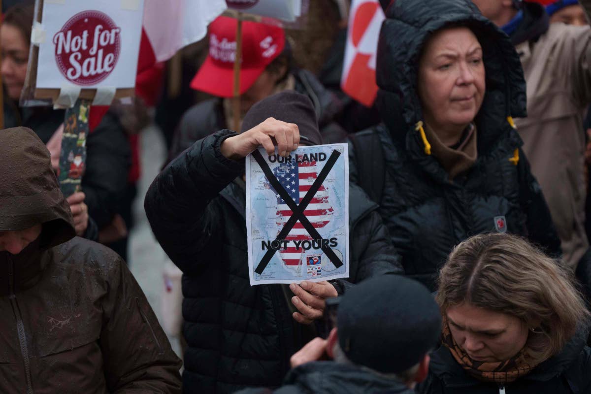 A man holds a map of Greenland covered in the American flag crossed out with an X during a protest against Trump’s policy towards Greenland in front of the US consulate in Nuuk, Greenland, Saturday, January 17, 2026. 