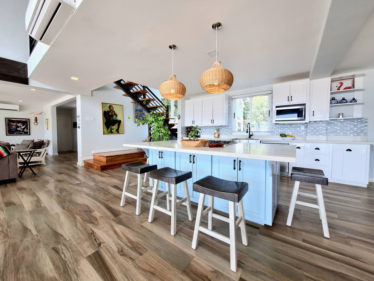 An open island kitchen anchors the space, with an interior balcony overlooking it from above.
