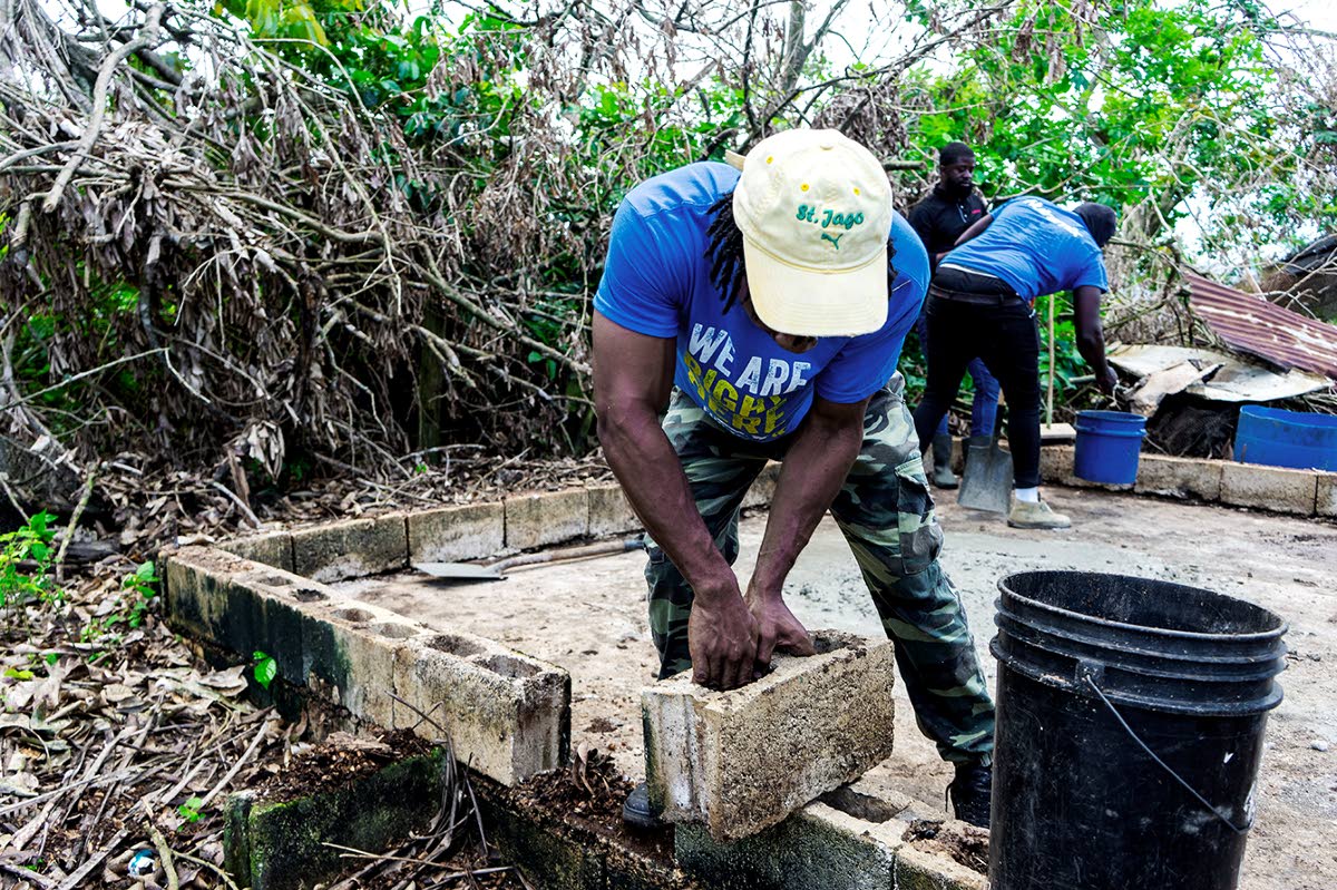 A Nutramix team member reinforces the foundation of a chicken coop being rebuilt in St Elizabeth following the passage of Hurricane Melissa.