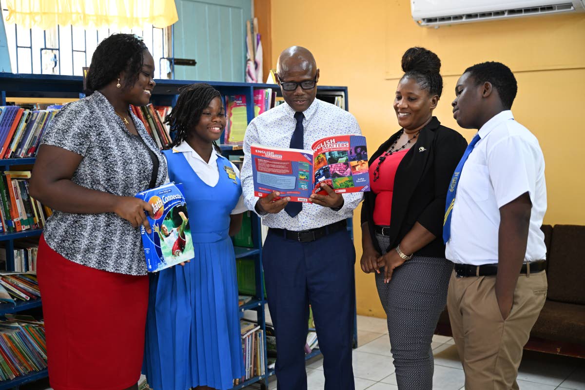 Principal of Prospect High School, Goffrey Flemming (centre), looks through an English textbook with Acting Head of the Language Department, Kimarie Copeland (left); student, Michelle Bowers; Mathematics teacher, Zandraleisha Eccleston (2nd right); and for