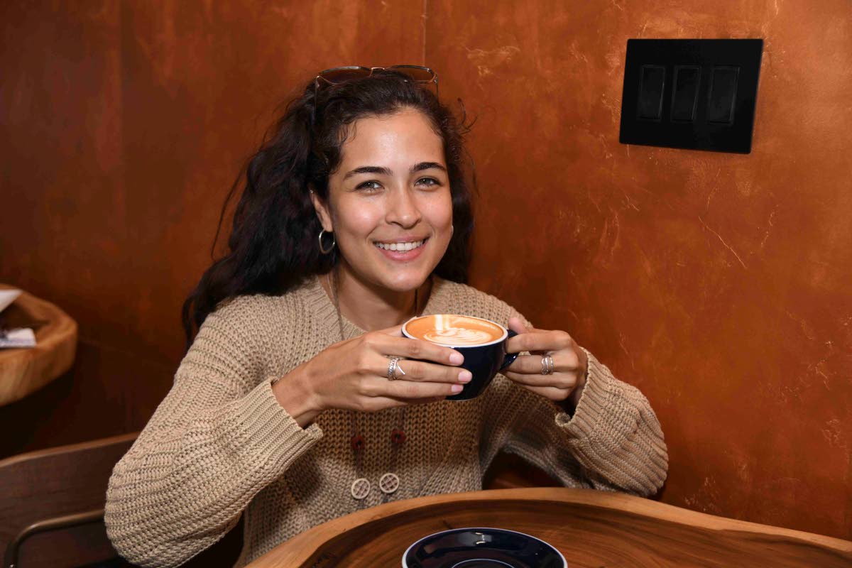Project engineer Zoe Chang enjoys a cup of latte at the 
opening of Cafe Blue’s New Kingston location on Monday.  