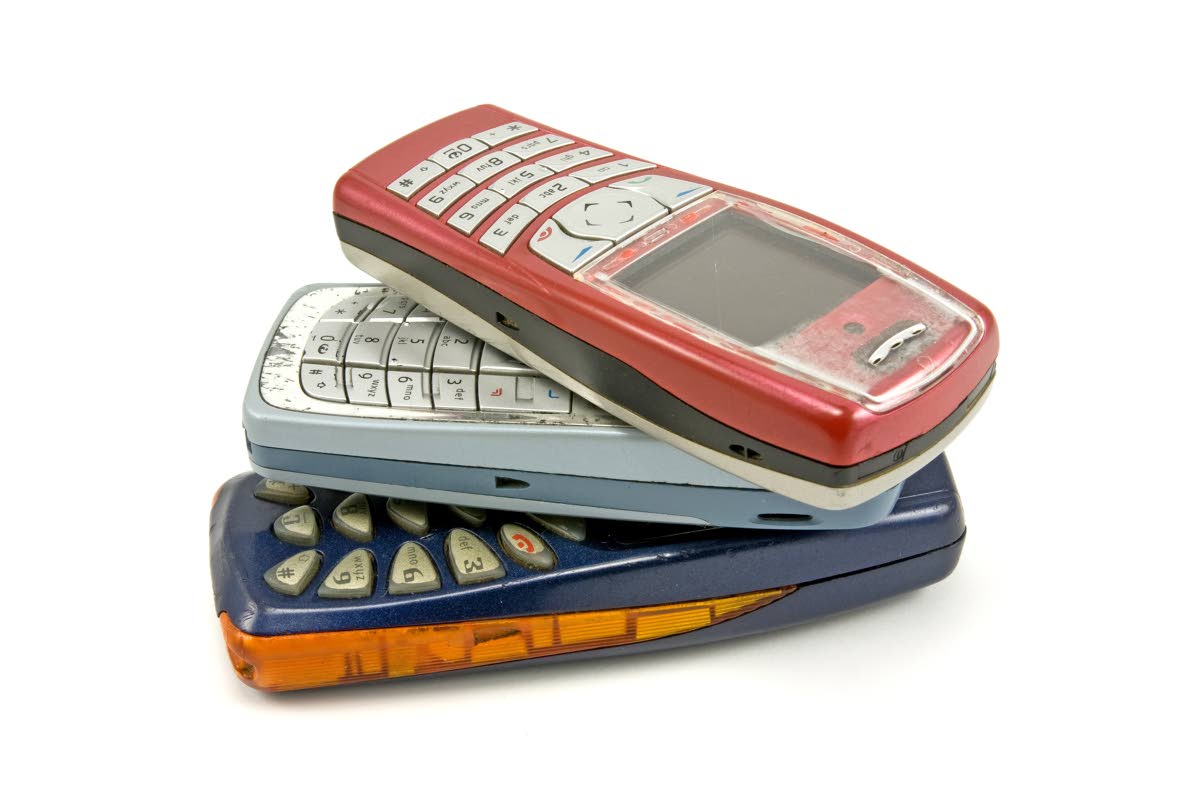 This stock photo shows old cellphones stacked on top of each other.