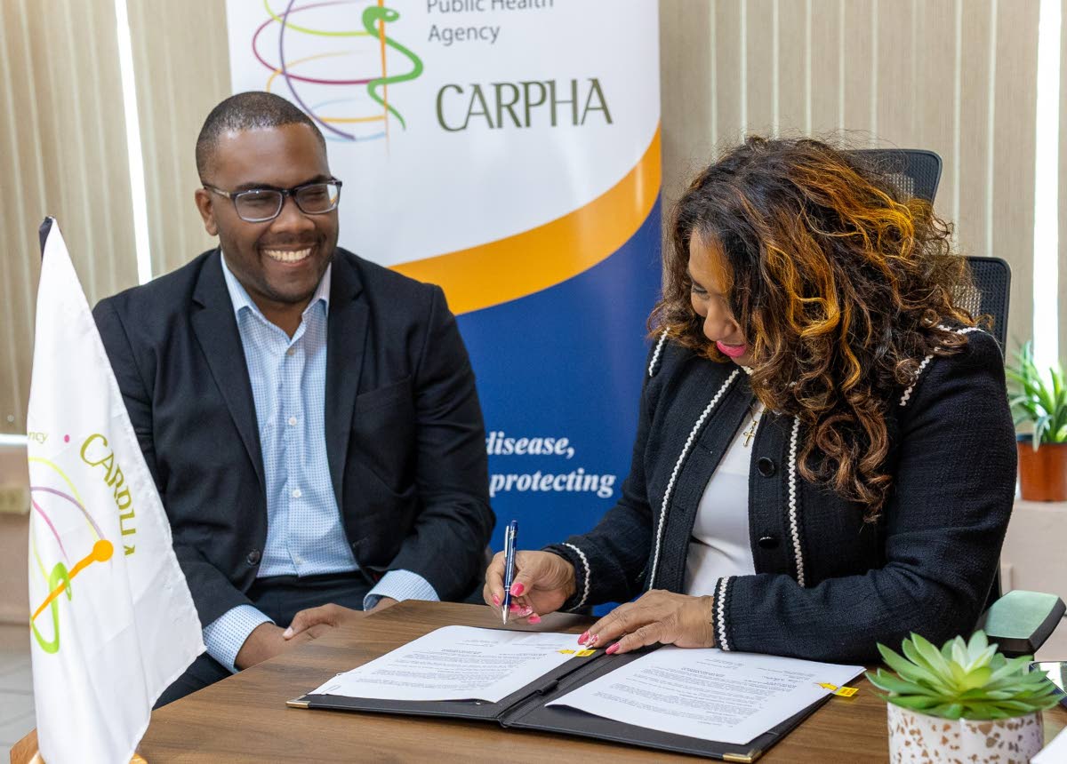 Dr Lisa Indar, CARPHA Executive Director, signs the Framework Agreement as Dr Horace Cox, director, watches, on February 13, 2026. 