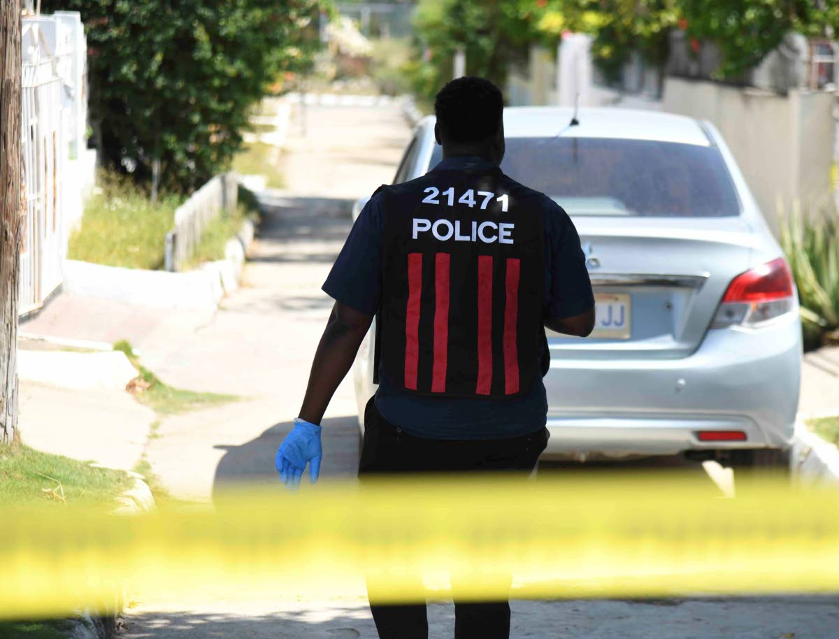A policeman approaches the house on Marlin Way in Braeton, Portmore in St Catherine yesterday, where a woman and her daughter were reportedly attacked by a man believed to be of unsound mind. The daughter was rushed to the hospital while the mother died in