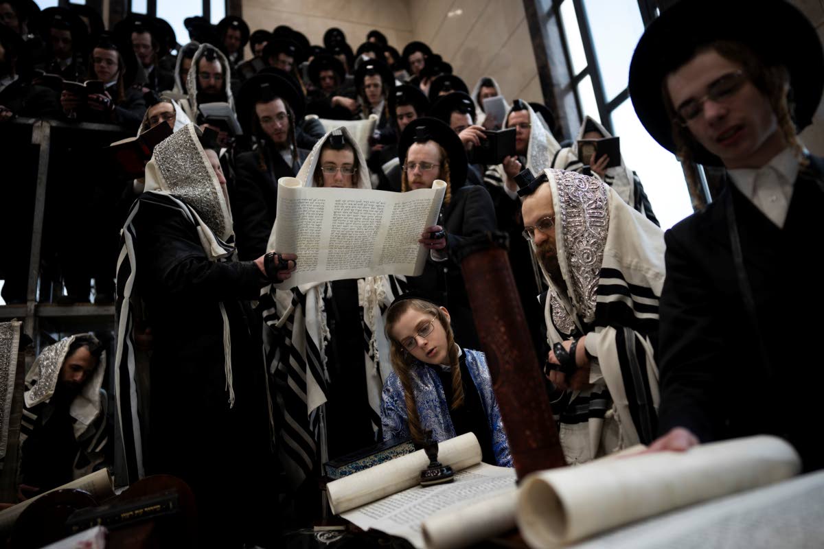 Jewish ultra-Orthodox men and children, some wearing costumes read the Book of Esther, which tells the story of the Jewish festival of Purim, at a synagogue in Bnei Brak, Israel, Friday, March 14, 2025. 