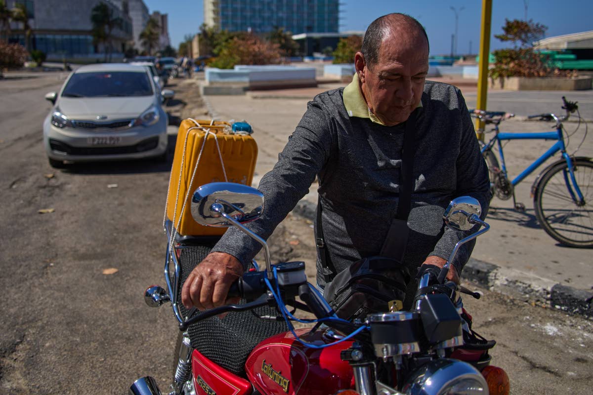 Retiree Jorge Reyes pushes his motorcycle to refuel it, as it’s his turn in line at a gas station in Havana, Cuba, last Monday. 