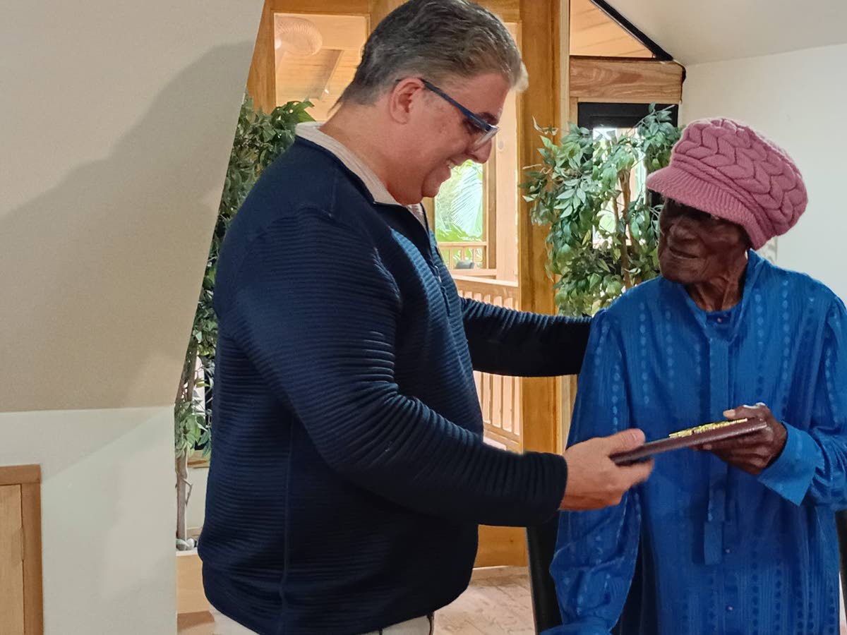 Centenarian Agnes Johnson speaks with St Ann Custos Joseph Issa as he presents her with a plaque. 