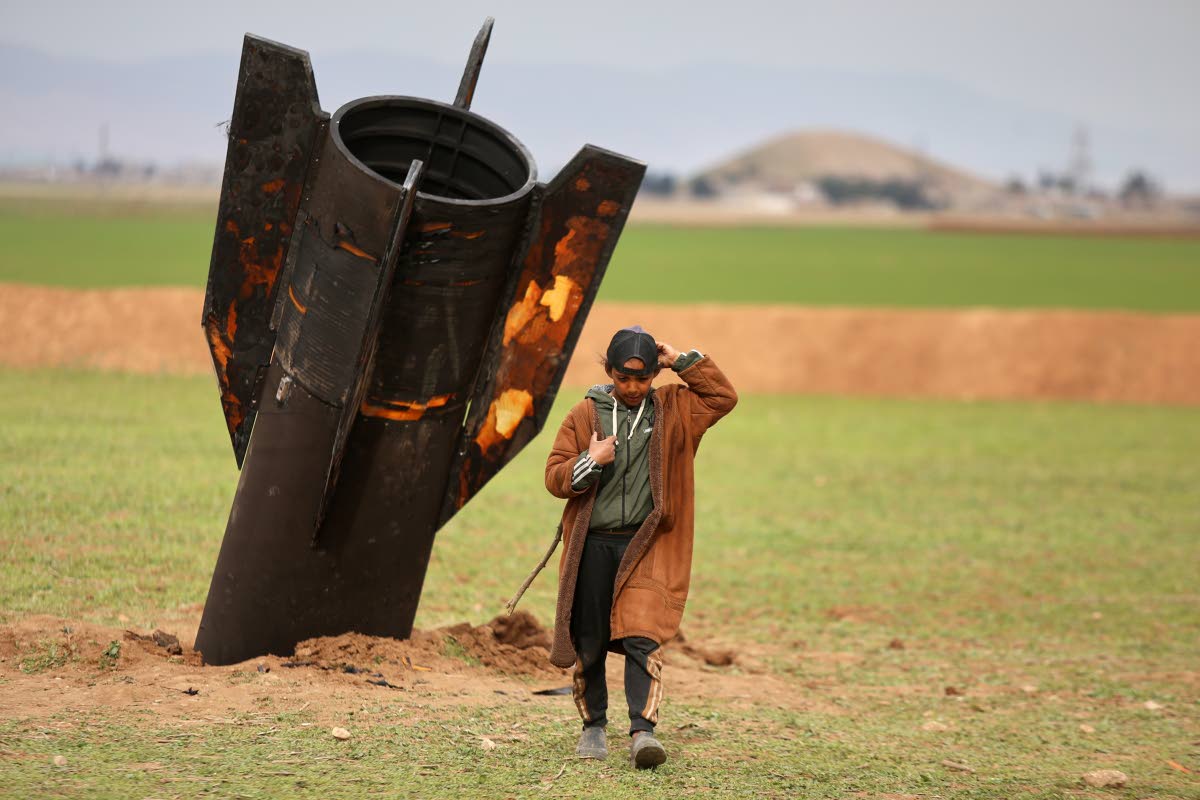 A shepherd boy walks away from an unexploded Iranian projectile that landed in an open field in the outskirts of Qamishli, eastern Syria.