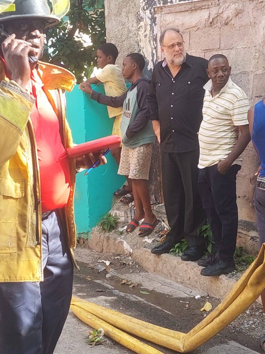 Member of Parliament for St Andrew South, Mark Golding (centre wearing black), in Craig Town where a fire destroyed several homes on March 8, 2026.